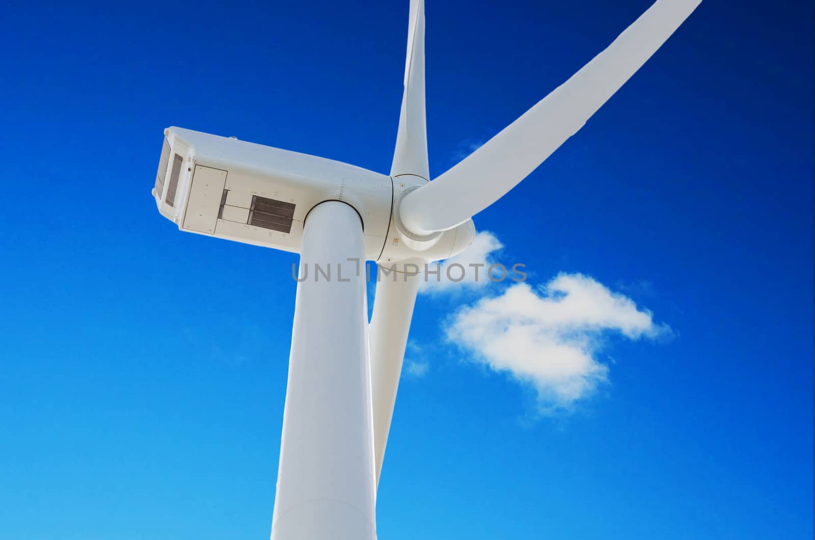 Wind turbine for electricity production, photographed from below against a blue sky.