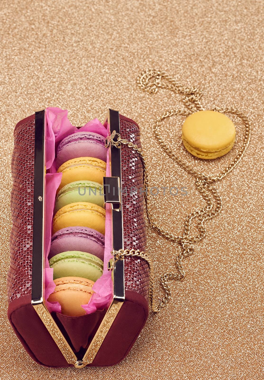 Macarons french in handbag. Luxury shiny glamor fashion clutch. Sweet colorful dessert. Unusual creative art, gold party background, bokeh, copyspase. Vintage