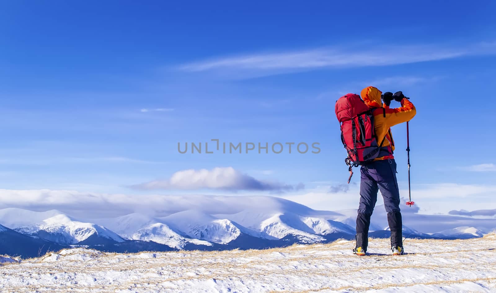 Hiker with a backpack takes a picture of mountain range in the background of the blue sky. Carpathian. Ukraine.