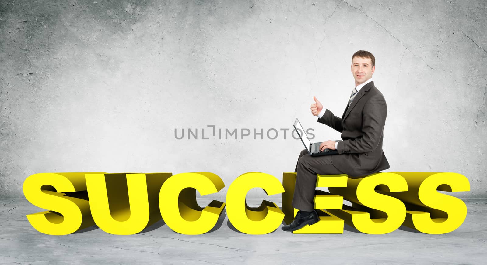 Businessman working on laptop and sitting on word success on grey wall background