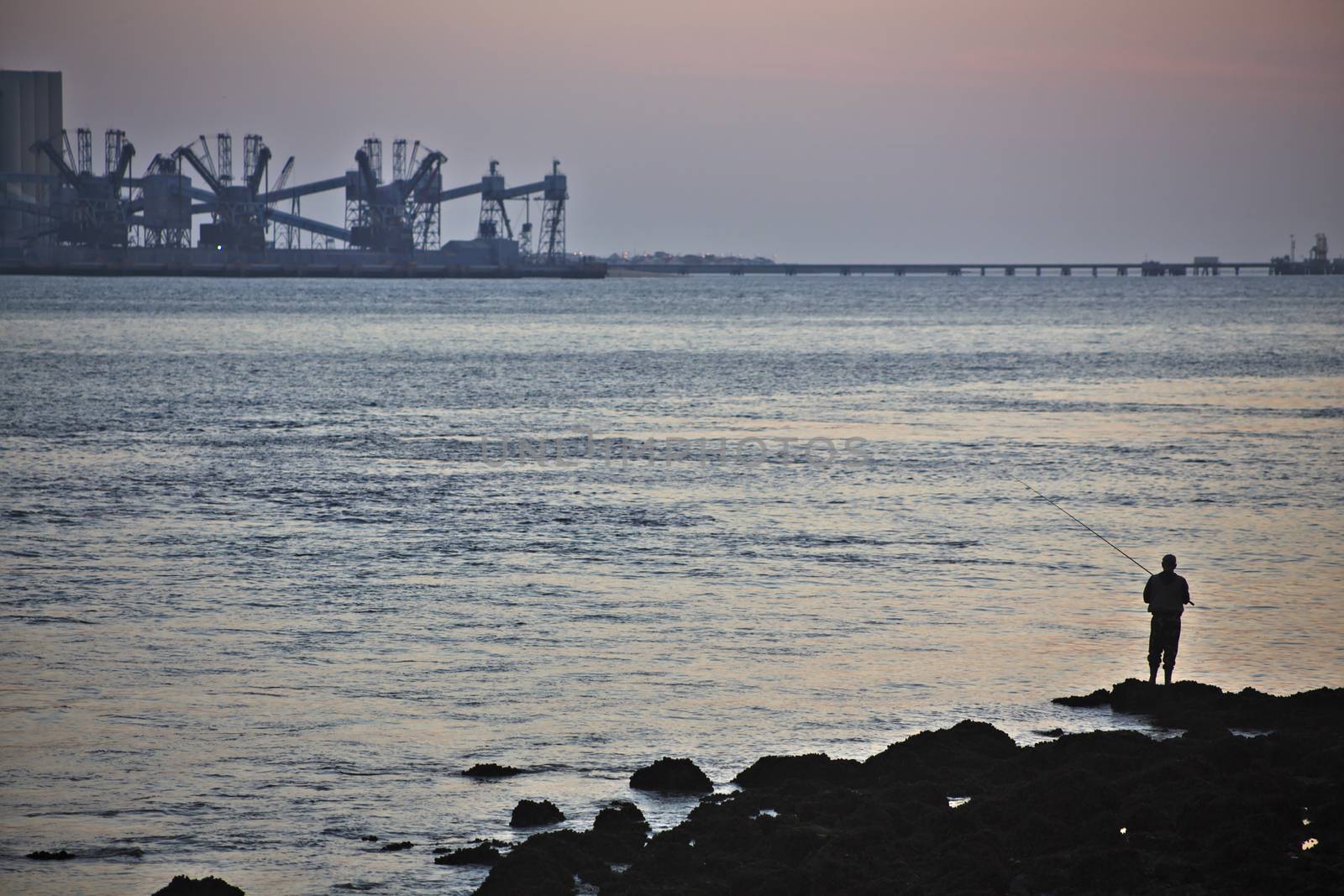 A fisherman at the mouth of the Tagus river trying to catch any prey.