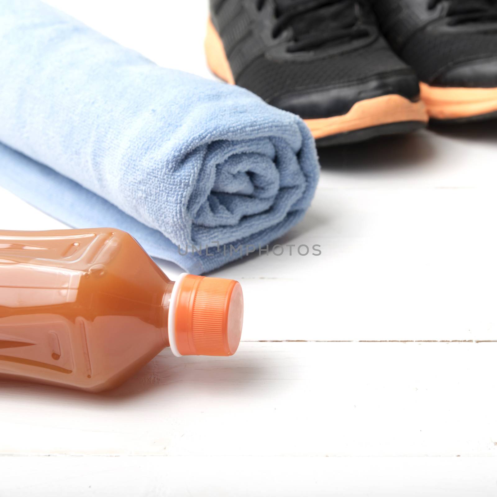 running shoes,towel and orange juice on white wood table