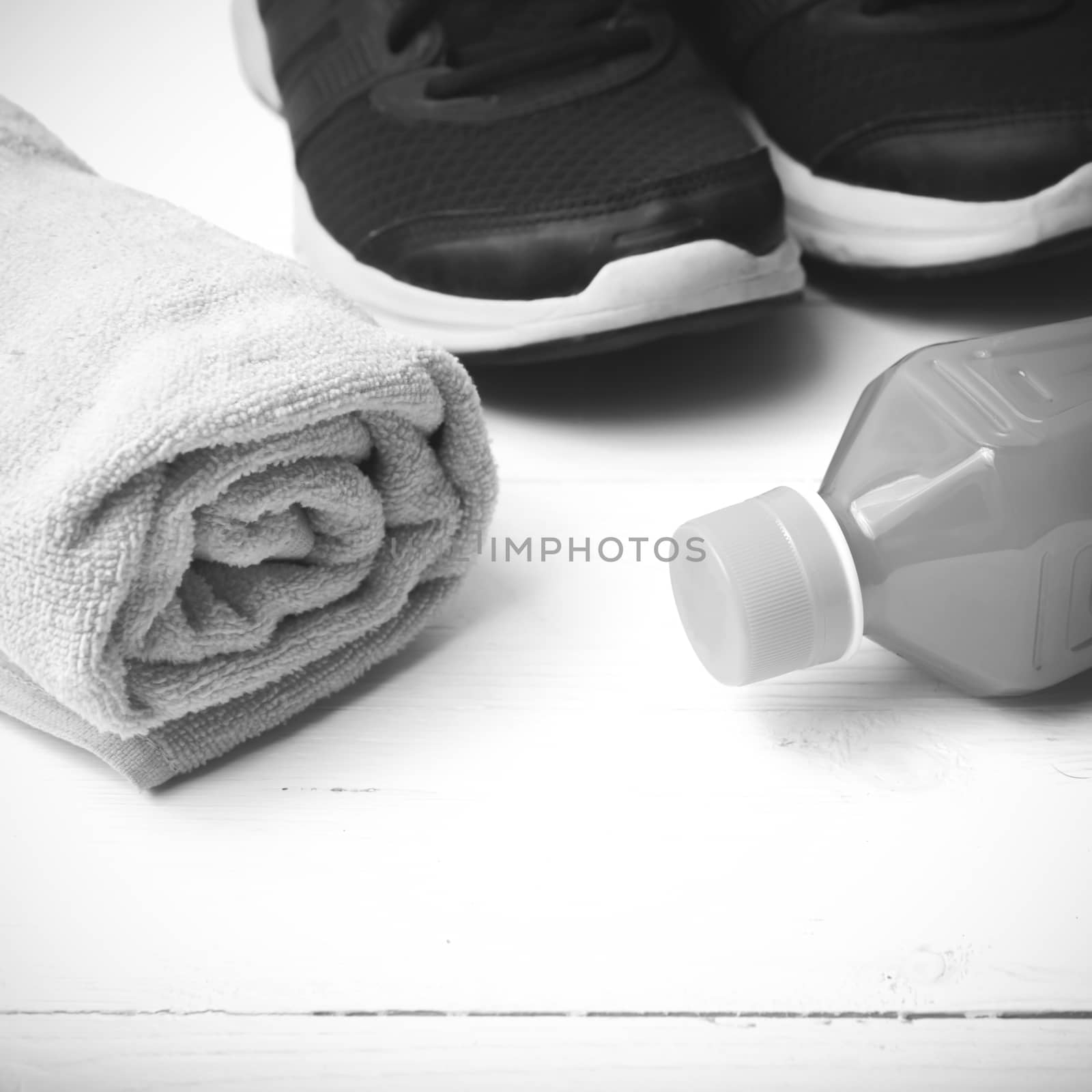 running shoes,towel and orange juice on white wood table black and white tone color style