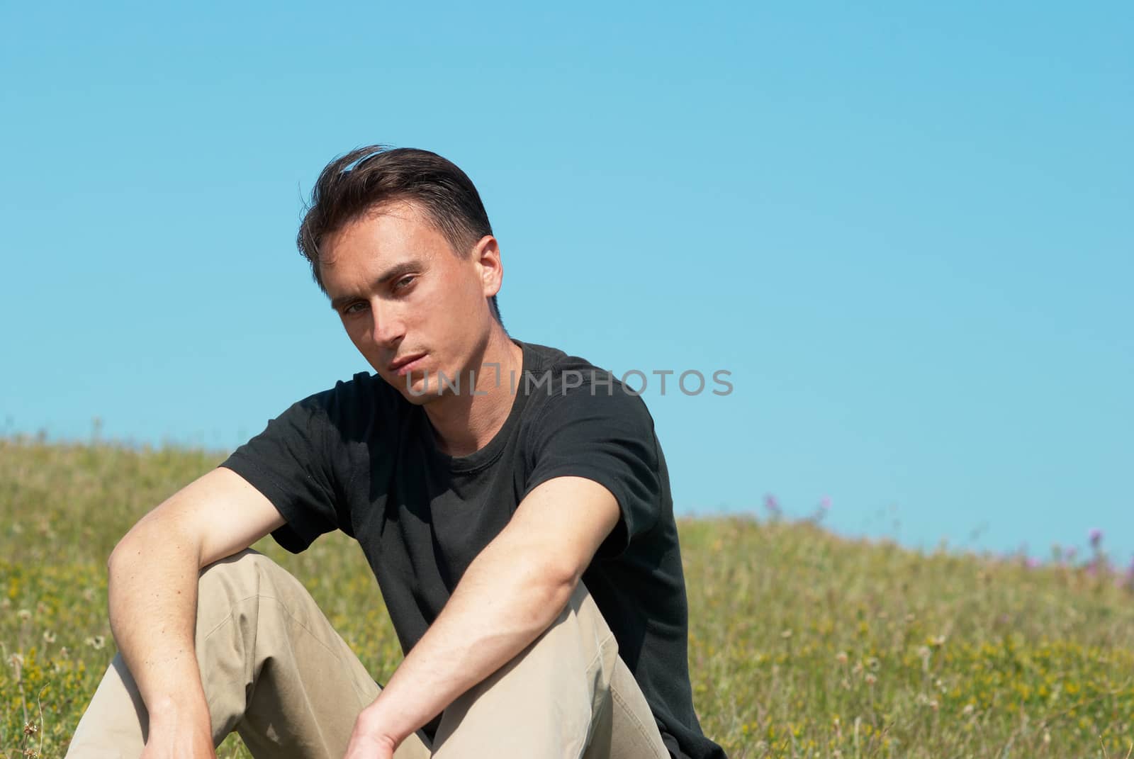 Young man sitting on the grass field by vapi