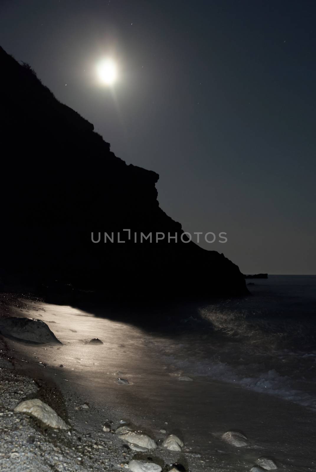 Moon night on the sea with waves and rocks.