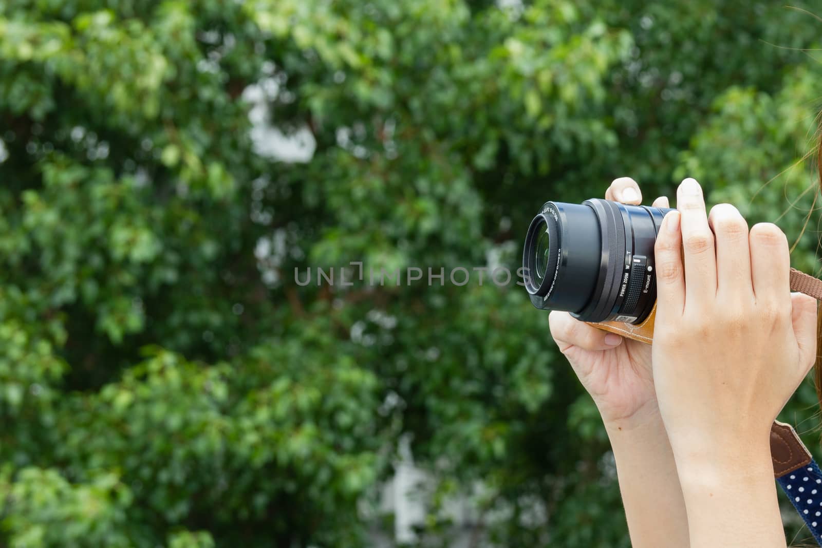 Lady take a photo with camera on her hand.