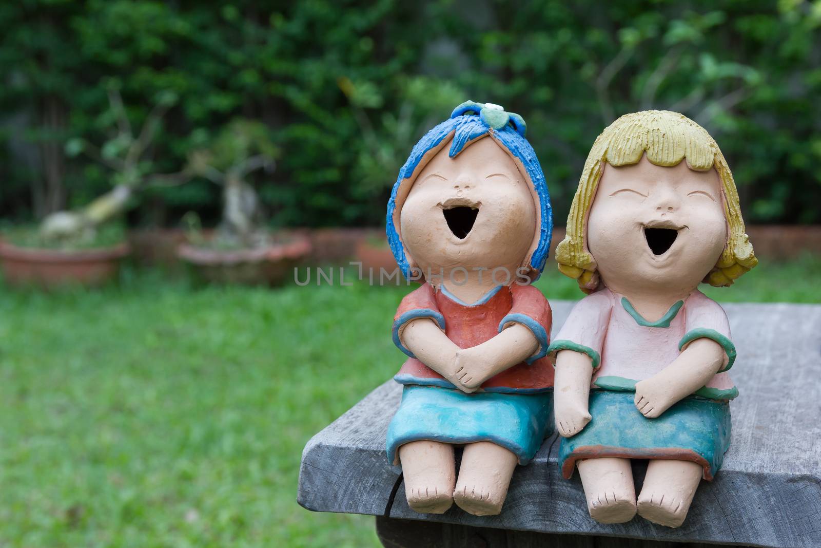 Laughing clay doll sit on the wooden chair