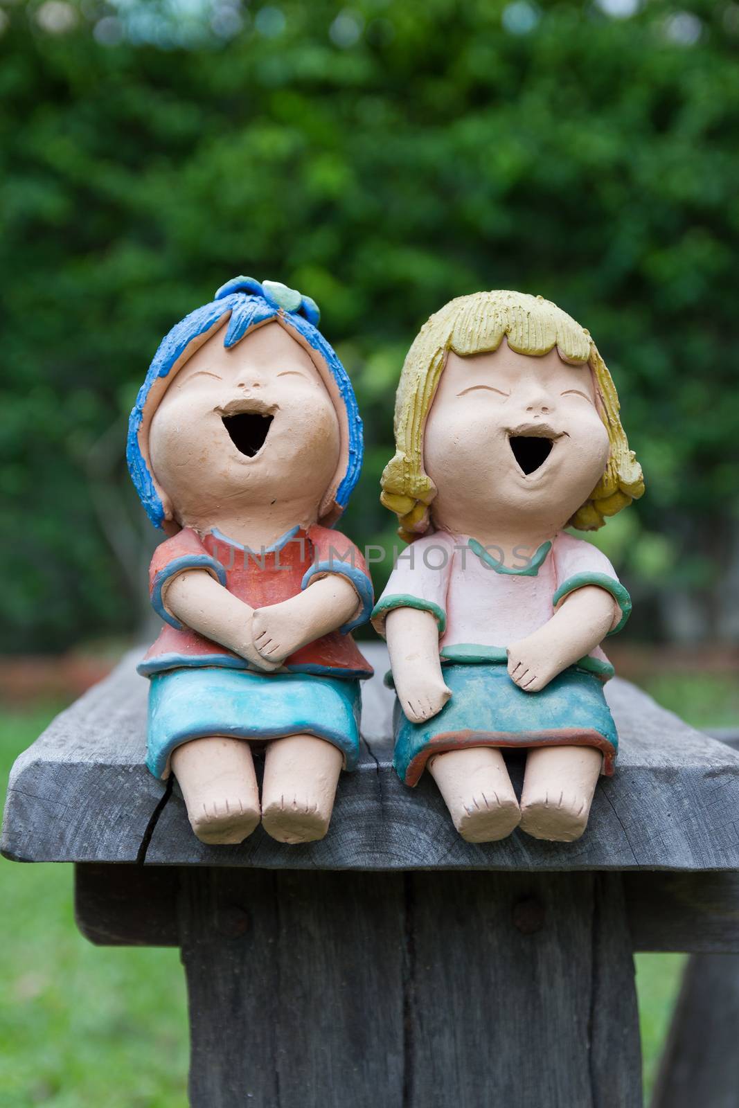 Laughing clay doll sit on the wooden chair