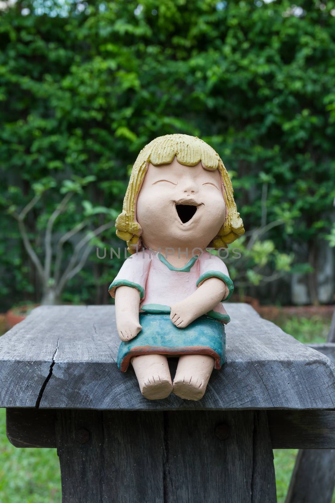 Laughing clay doll sit on the wooden chair