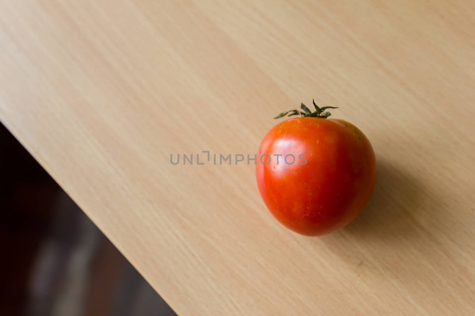 A fresh tomato on the wooden table.