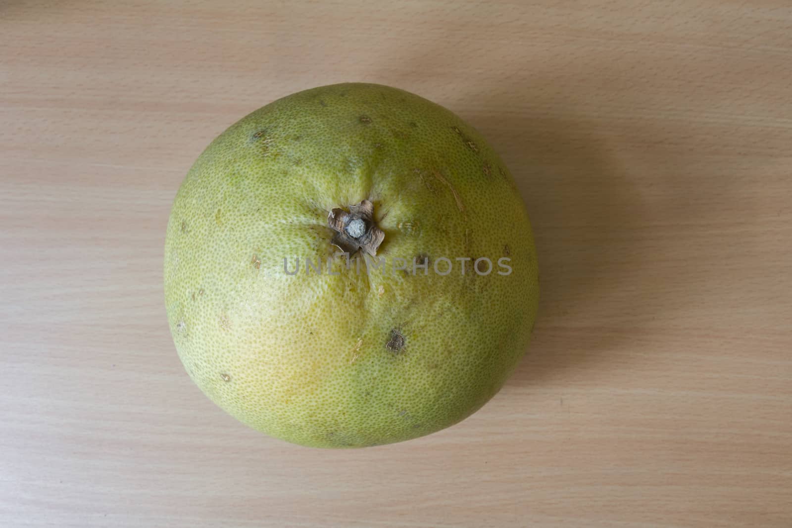 A fresh pomelo on the wooden desk.