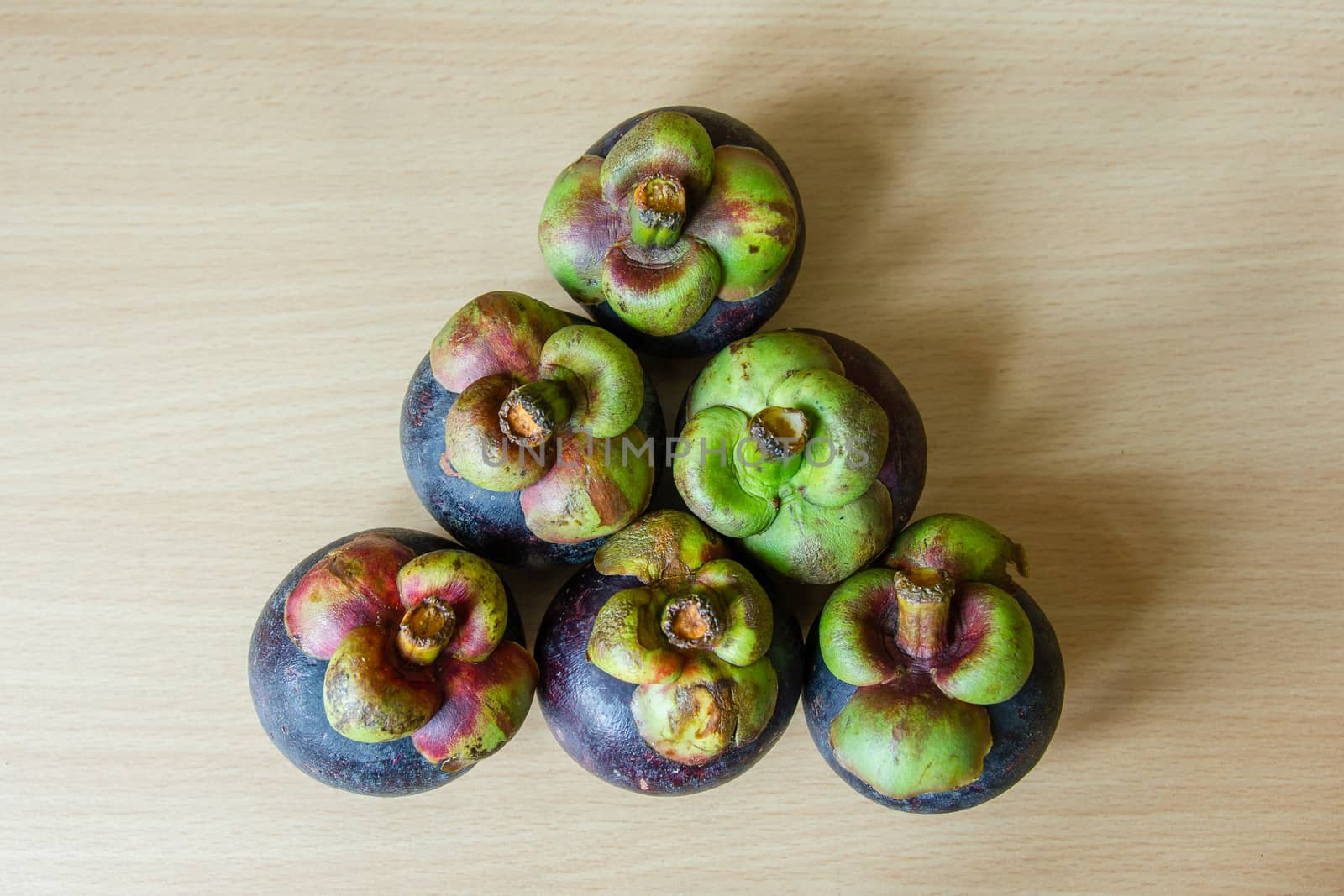 Pile of fresh mangosteen place on a wooden table.