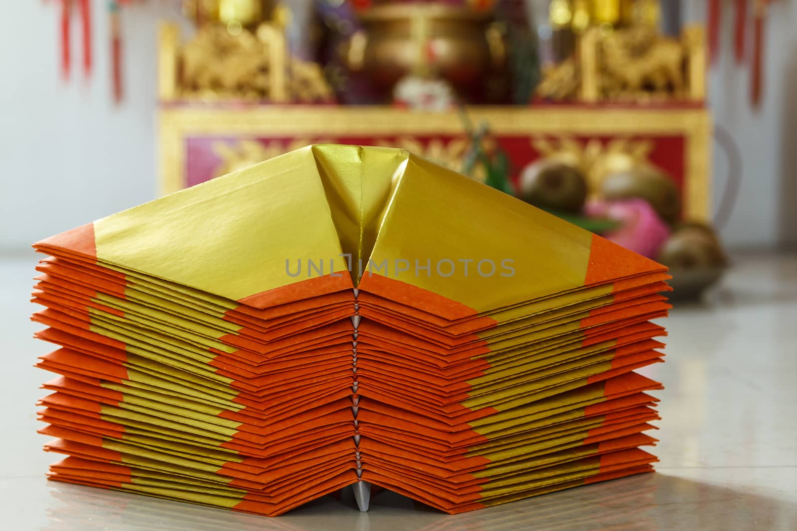 Chinese paper art use for worship.And a shrine in the background.Focus on the top  paper.