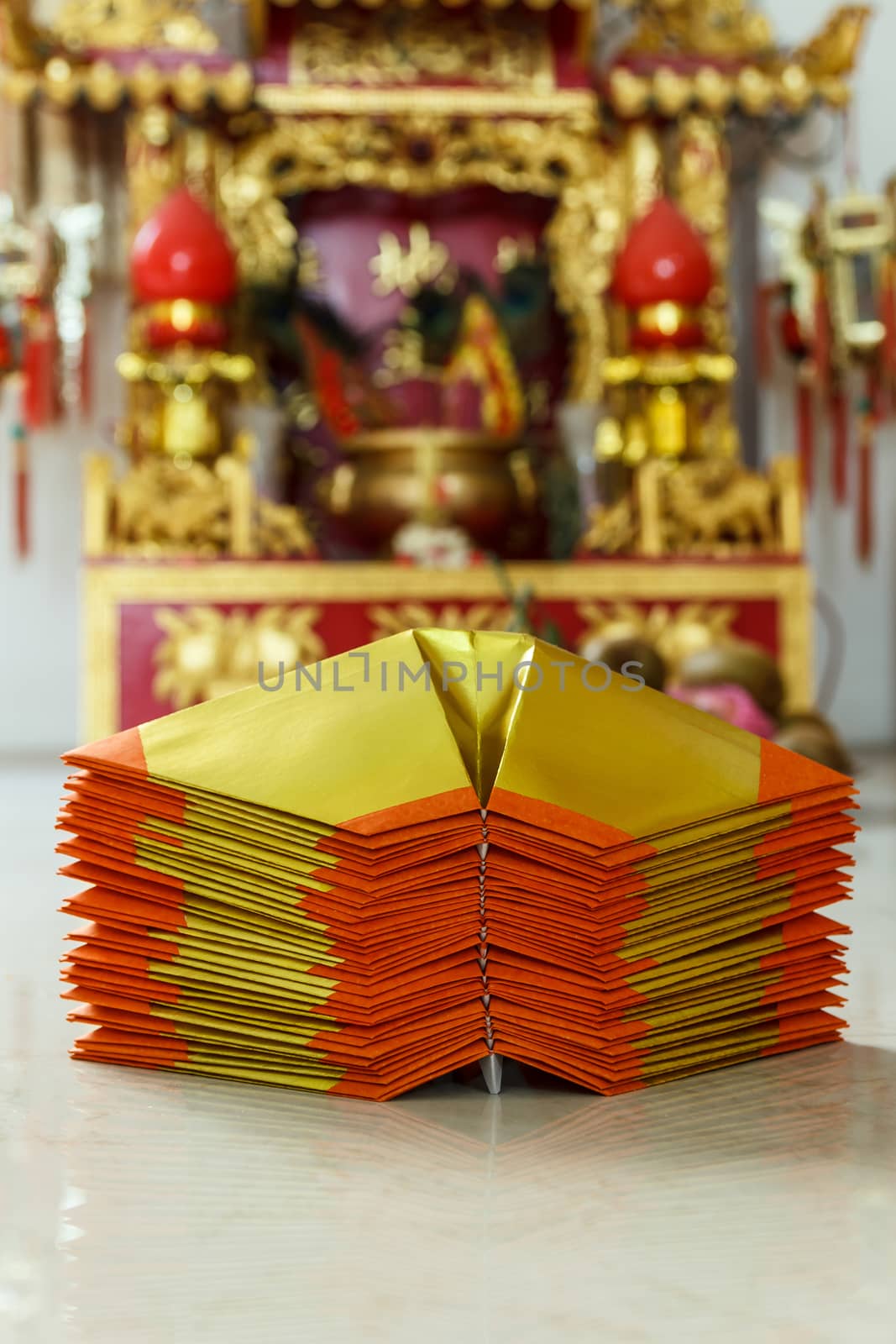 Chinese paper art use for worship.And a shrine in the background.Focus on the top paper.