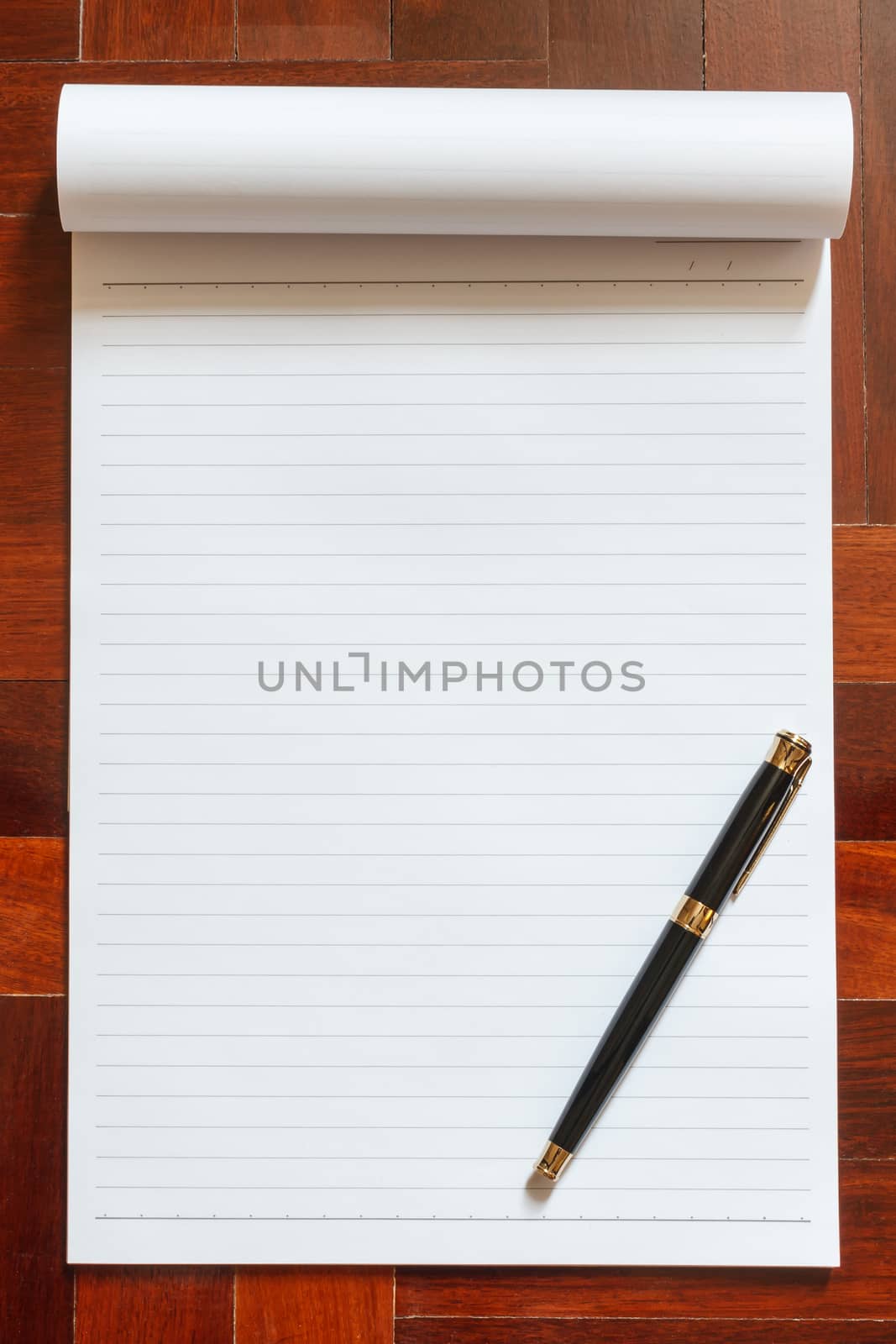 Notebook blank white page and pen. Wooden floor in the background.