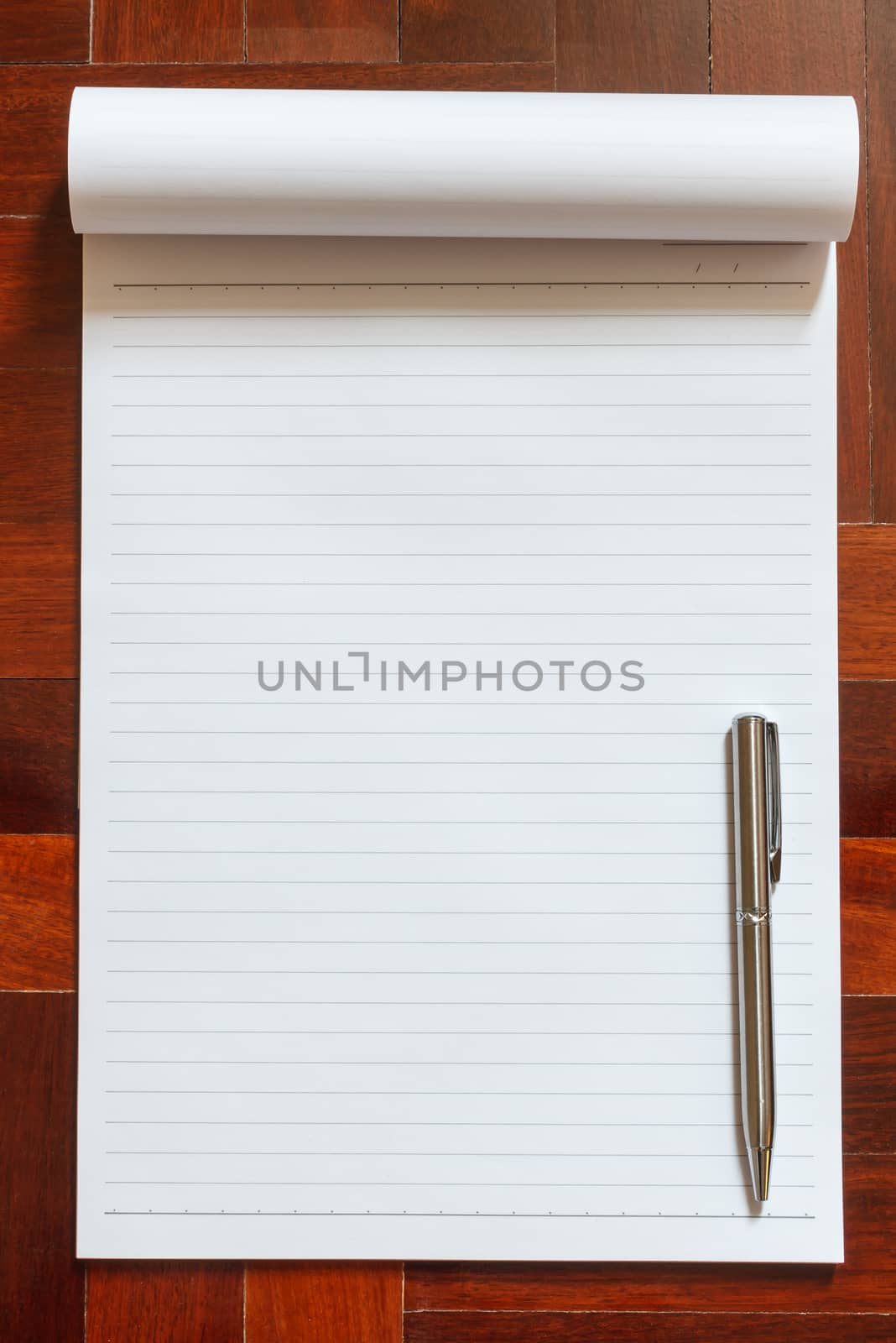 Notebook blank white page and pen. Wooden floor in the background.