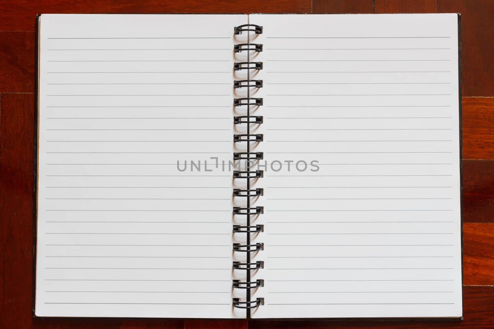 Notebook blank white page. Wooden floor in the background.