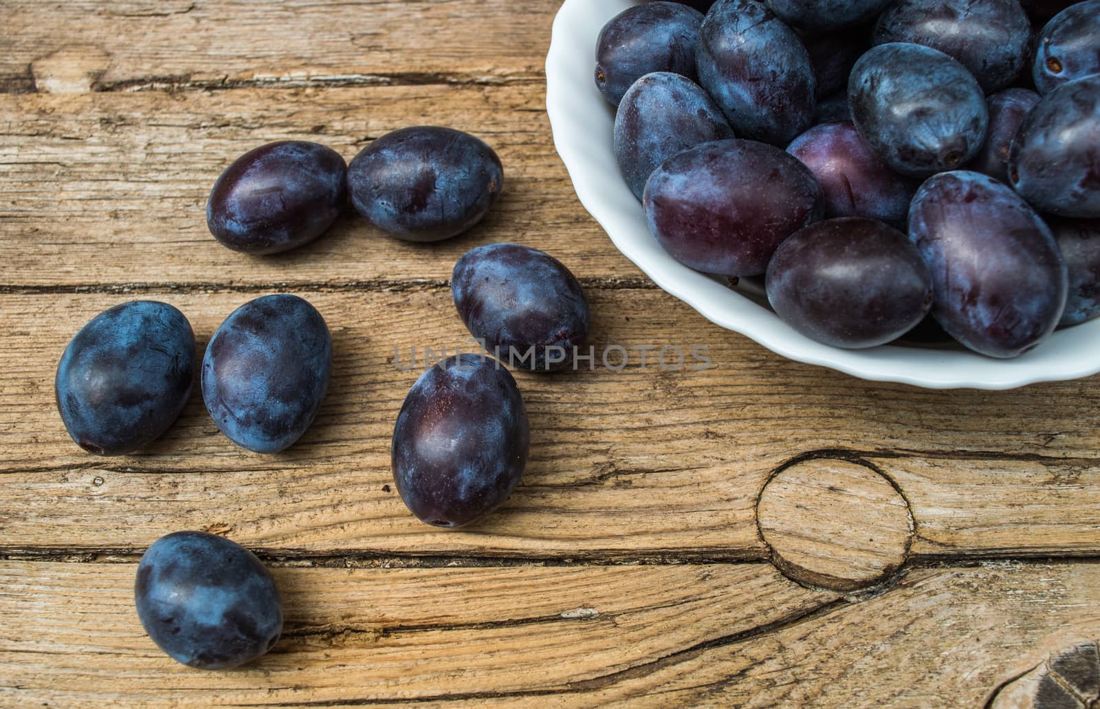 Plate full of fresh plums on a wooden background  by radzonimo