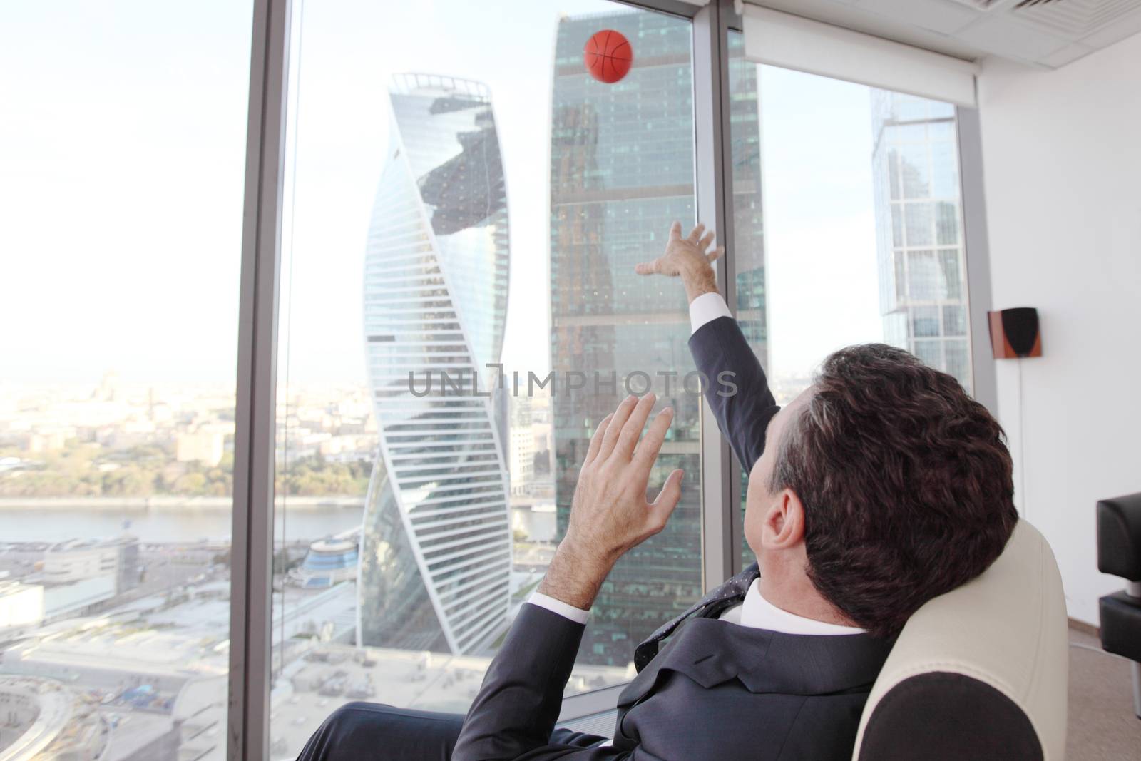 Business man playing with a basketball at the office