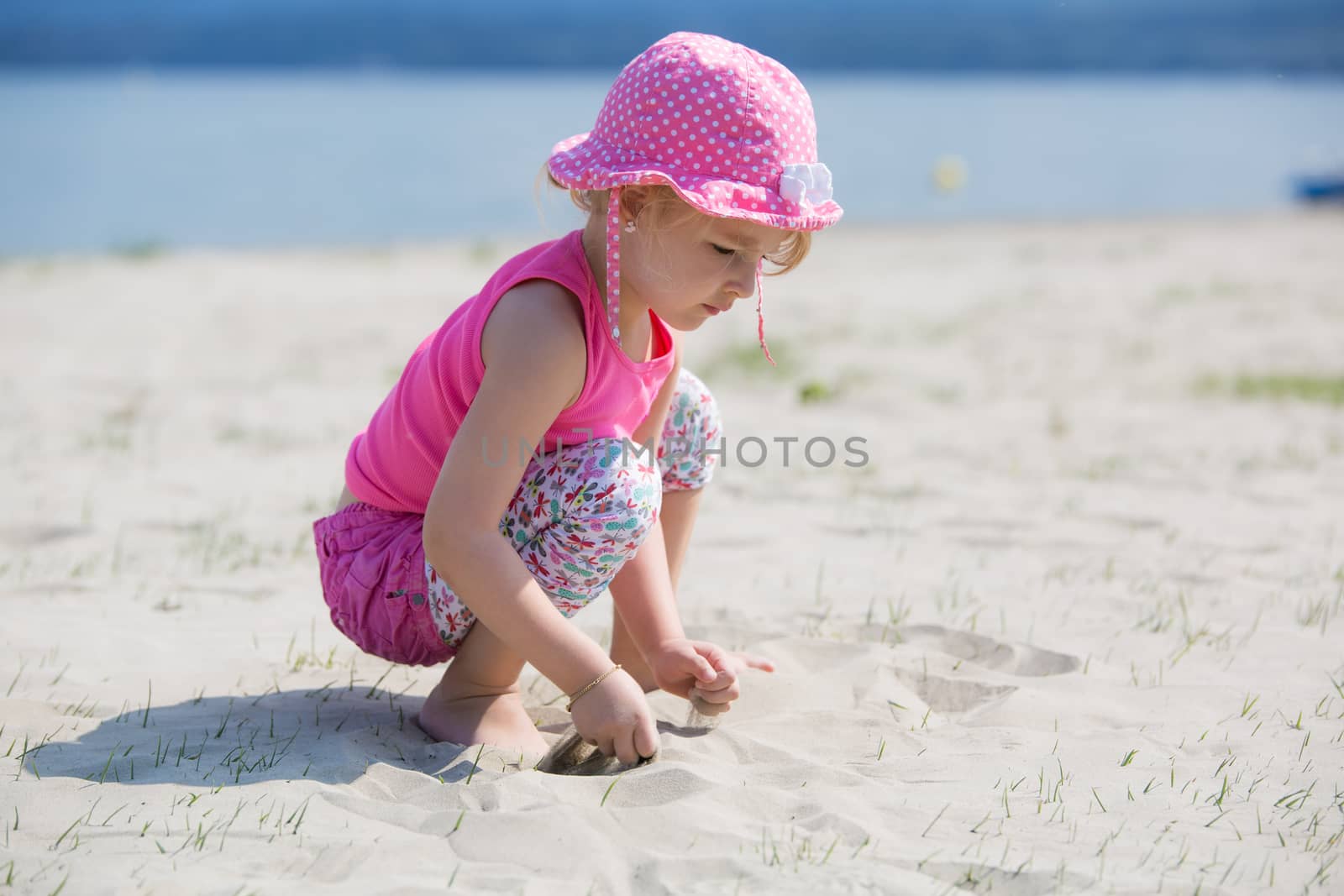 Young blond girl playing in the sand on a beach