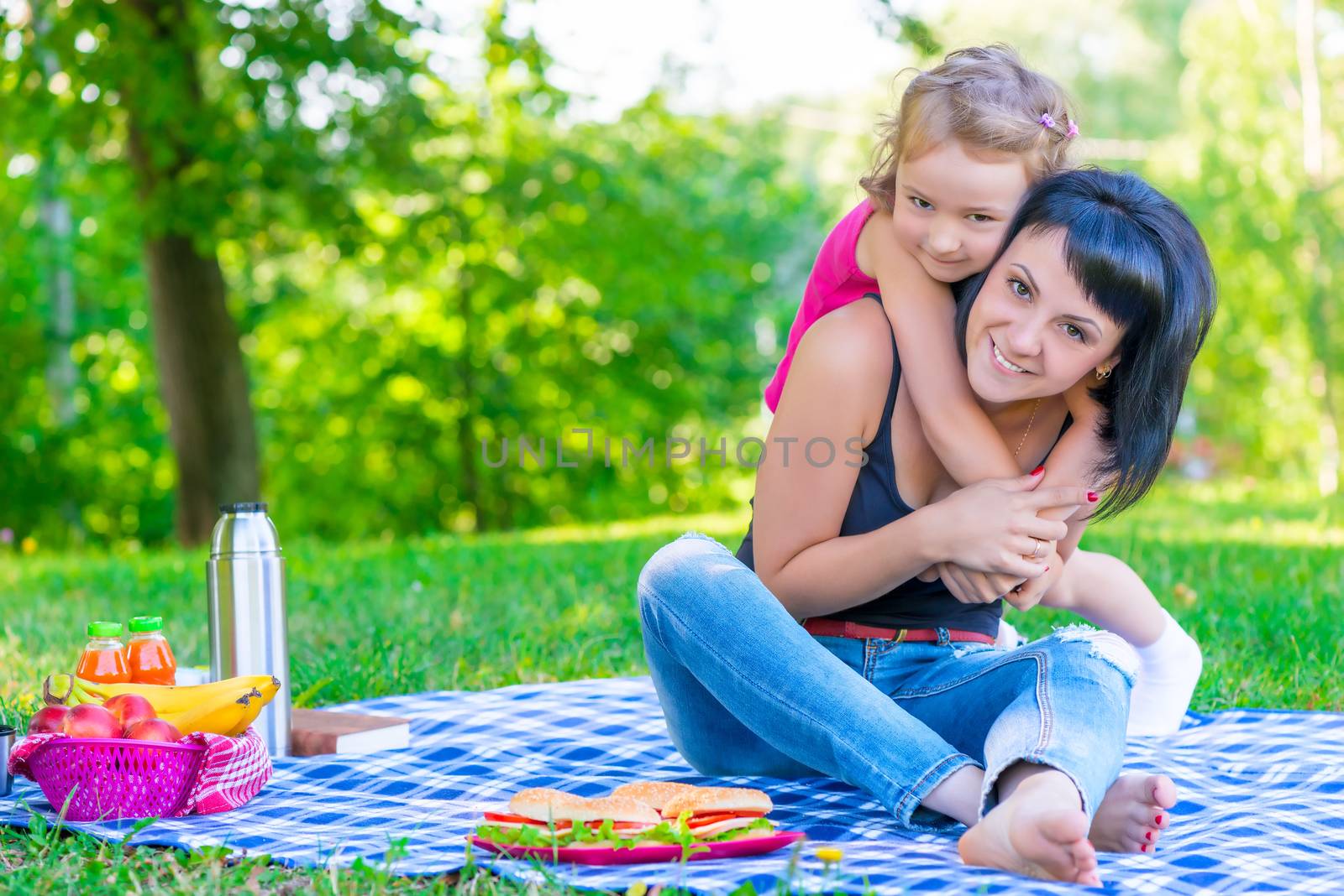 little daughter hugging her mother relaxing in the park