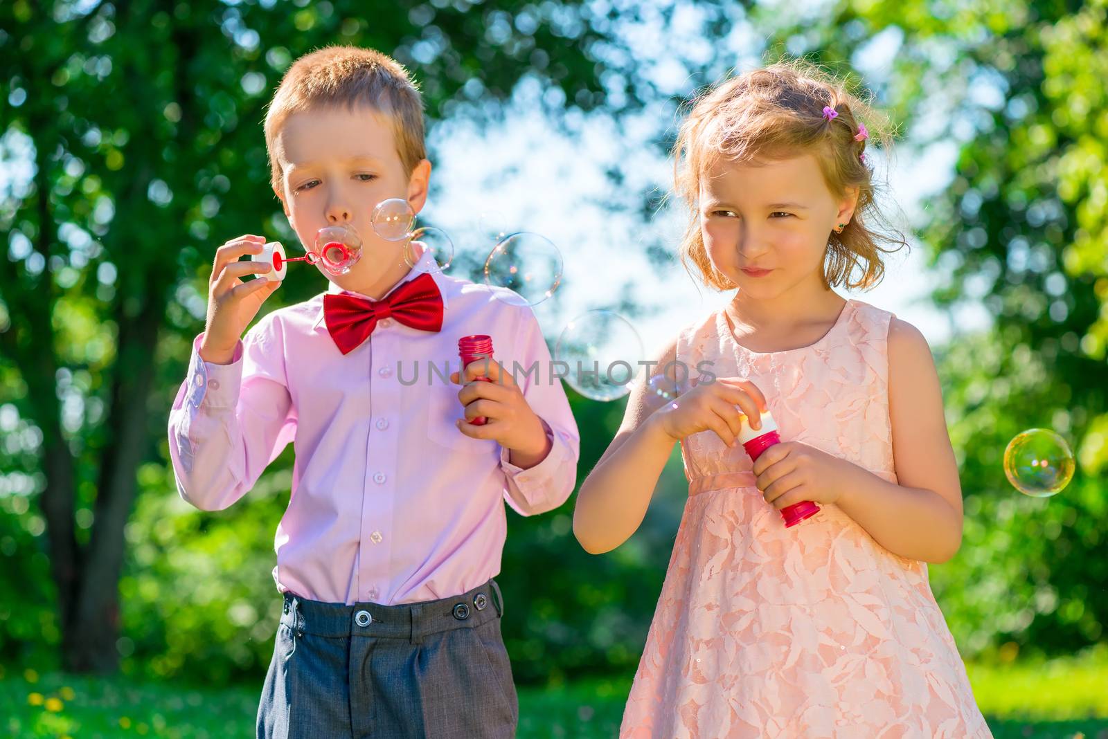 Children 6 years old doing soap bubbles in the park