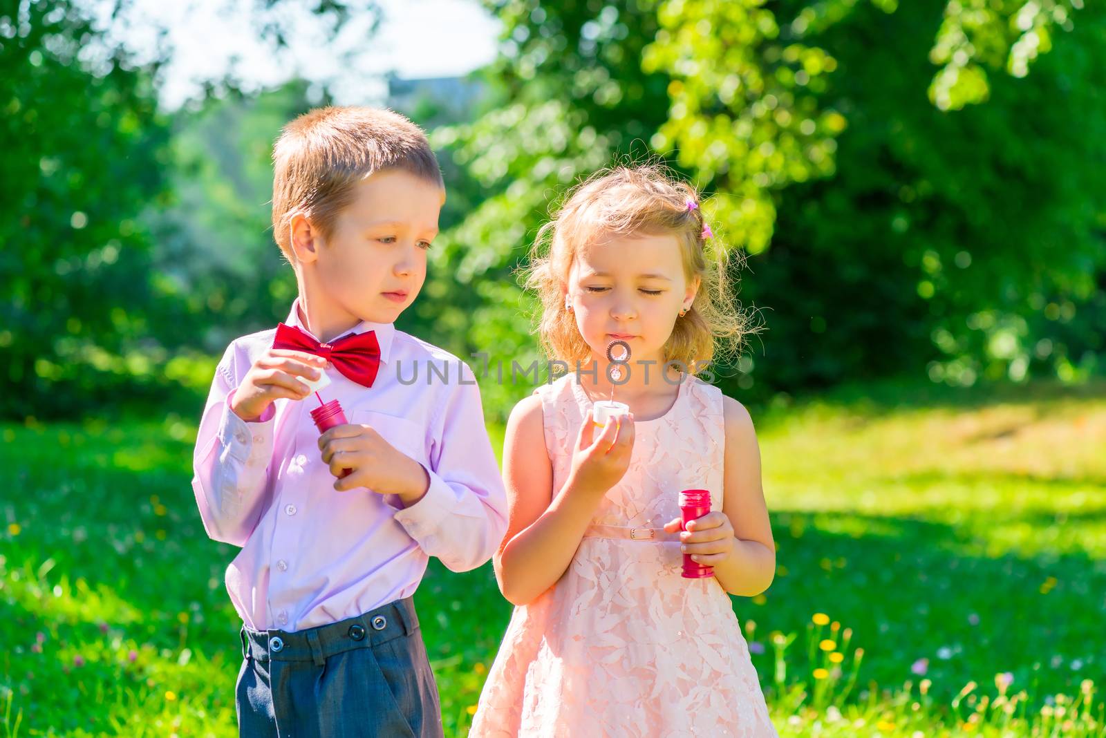 six year old boy looks at the girl makes soap bubbles