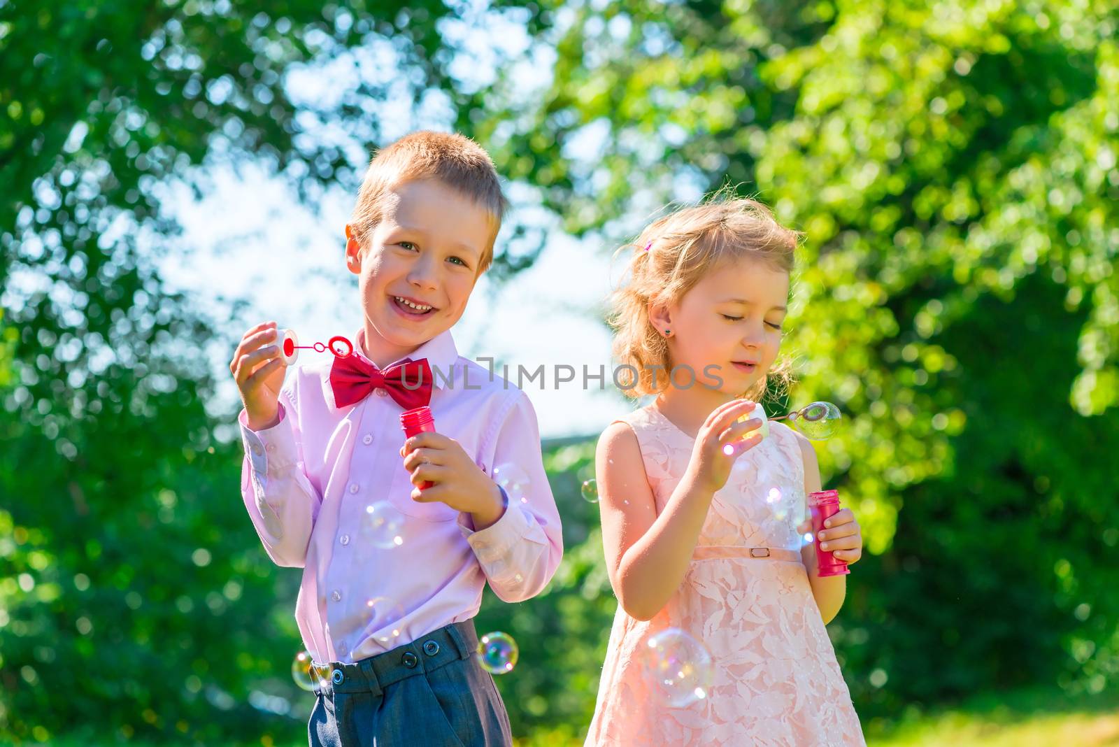 Happy children play with soap bubbles on the lawn