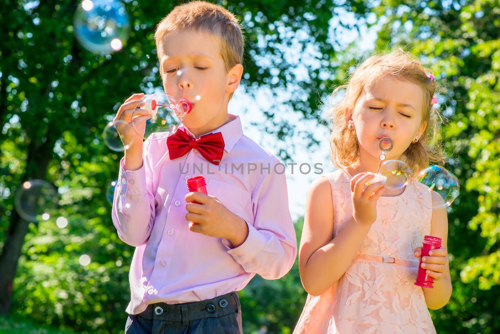 children at the celebration with soap bubbles on a summer day