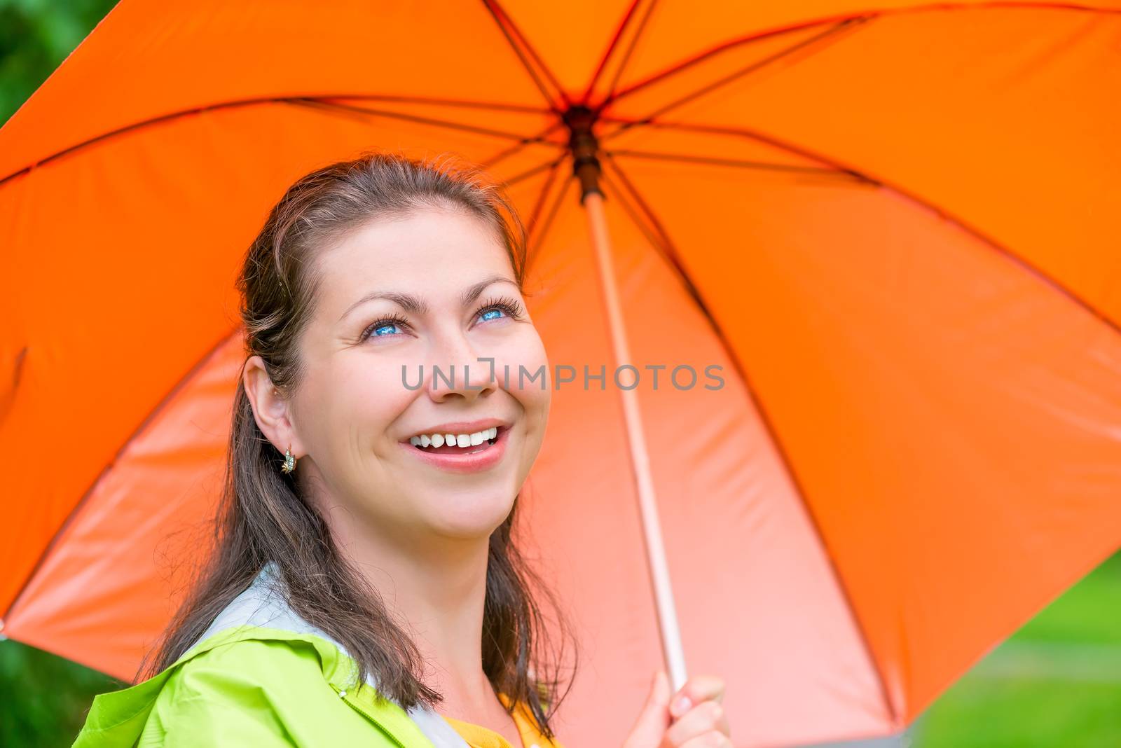 laughing pretty girl with an orange umbrella walking in the rain