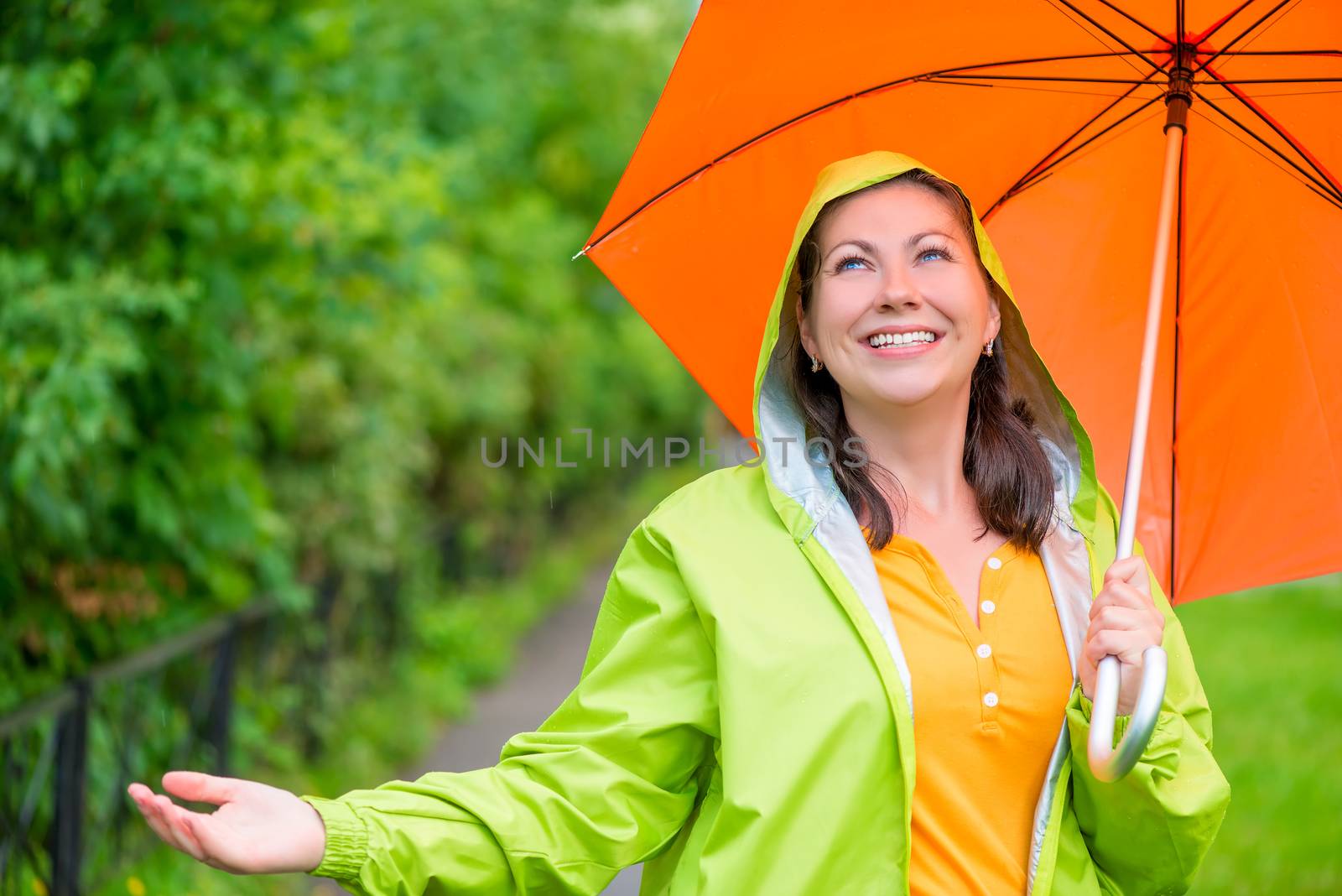 portrait of a beautiful girl with an umbrella and a raincoat on the nature