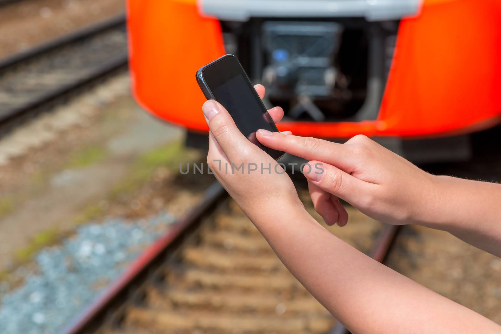 touchscreen mobile phone in female hands on a background of train