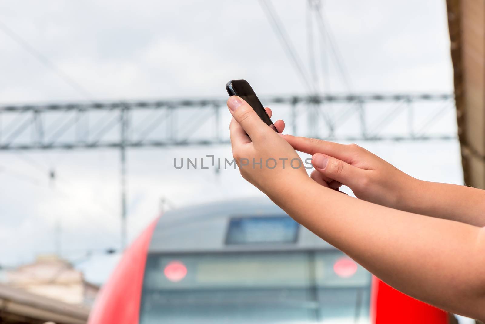 hands close-up with a mobile phone at railway station