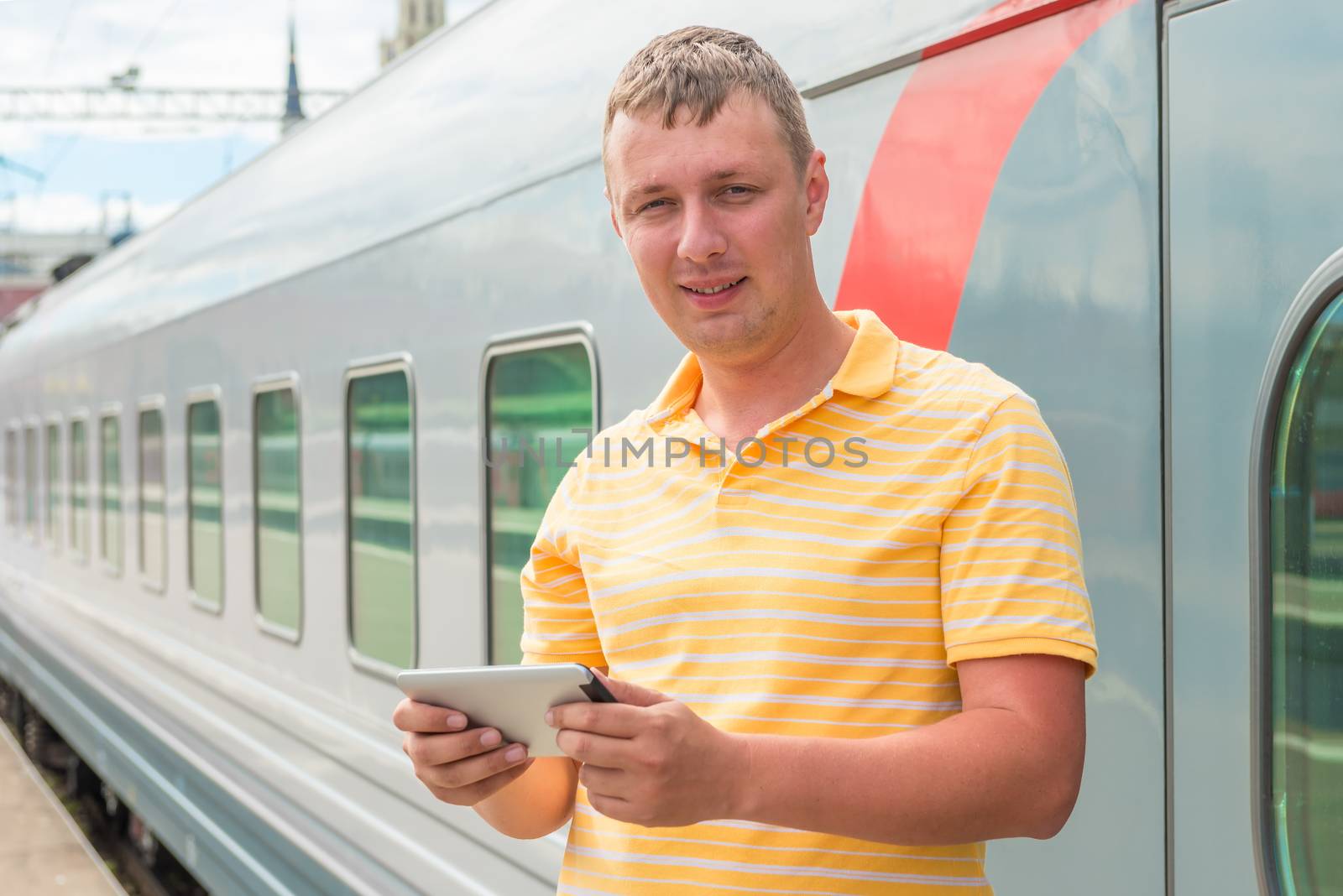 Happy man holding a tablet computer near the train by kosmsos111