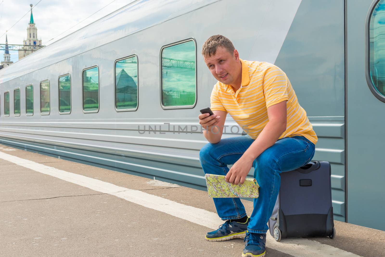 man sitting on a suitcase at the railway station