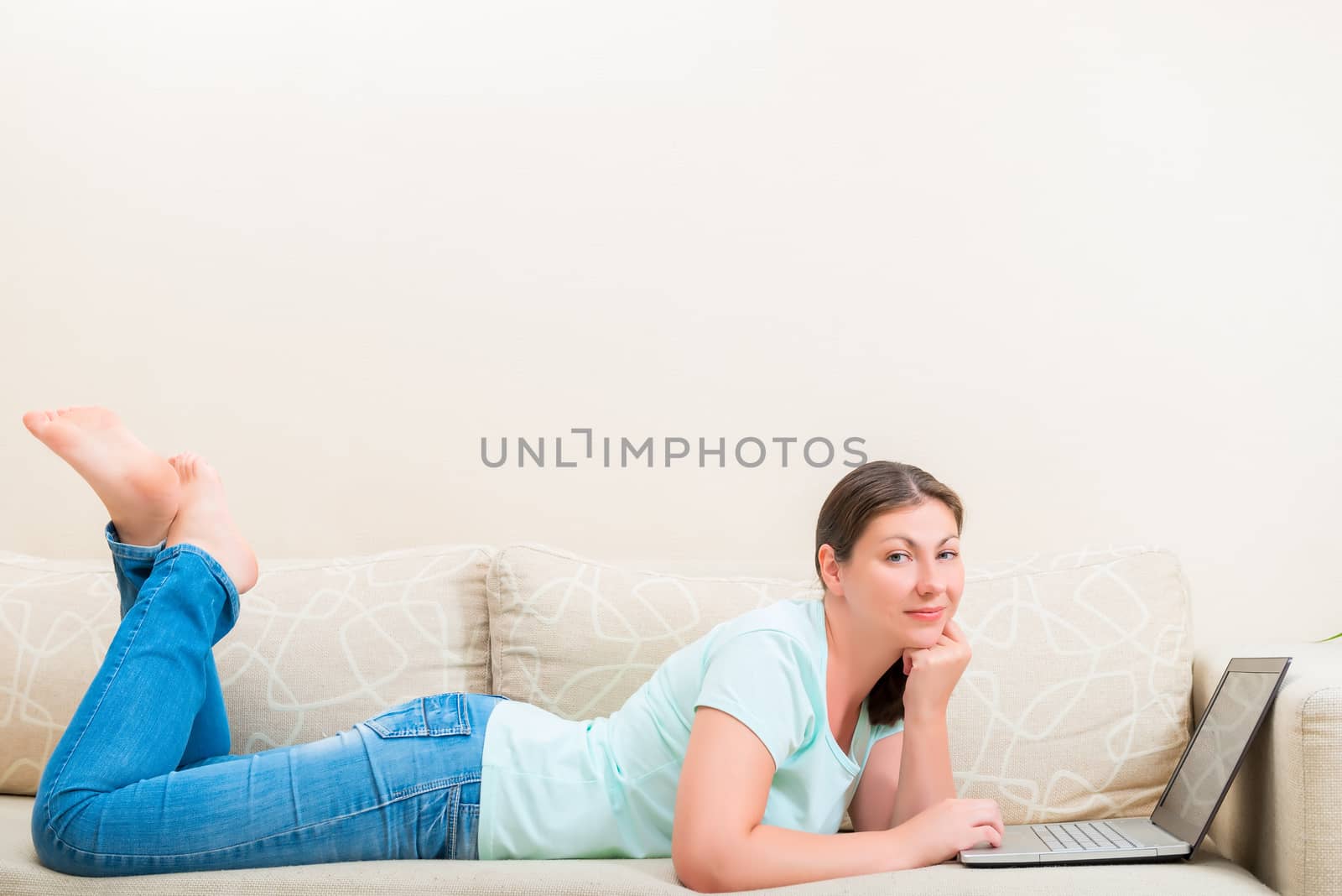 girl in jeans and a T-shirt on the couch with a laptop by kosmsos111