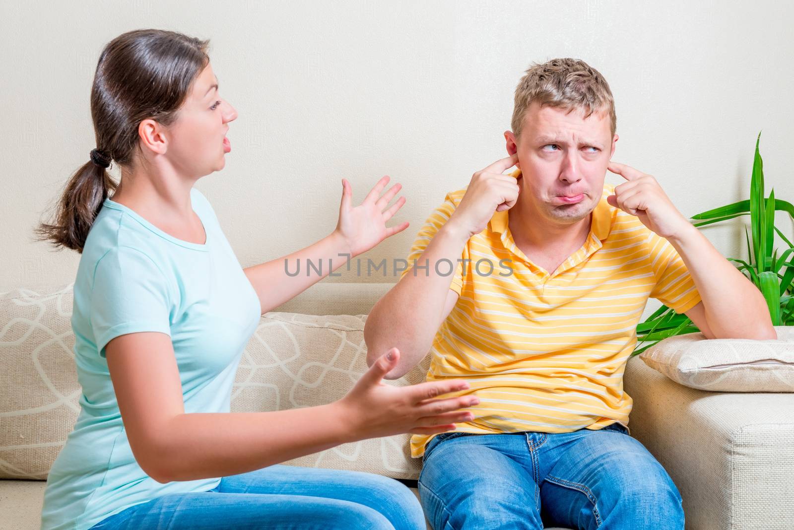 wife scolds her husband sitting on a sofa in the living room by kosmsos111