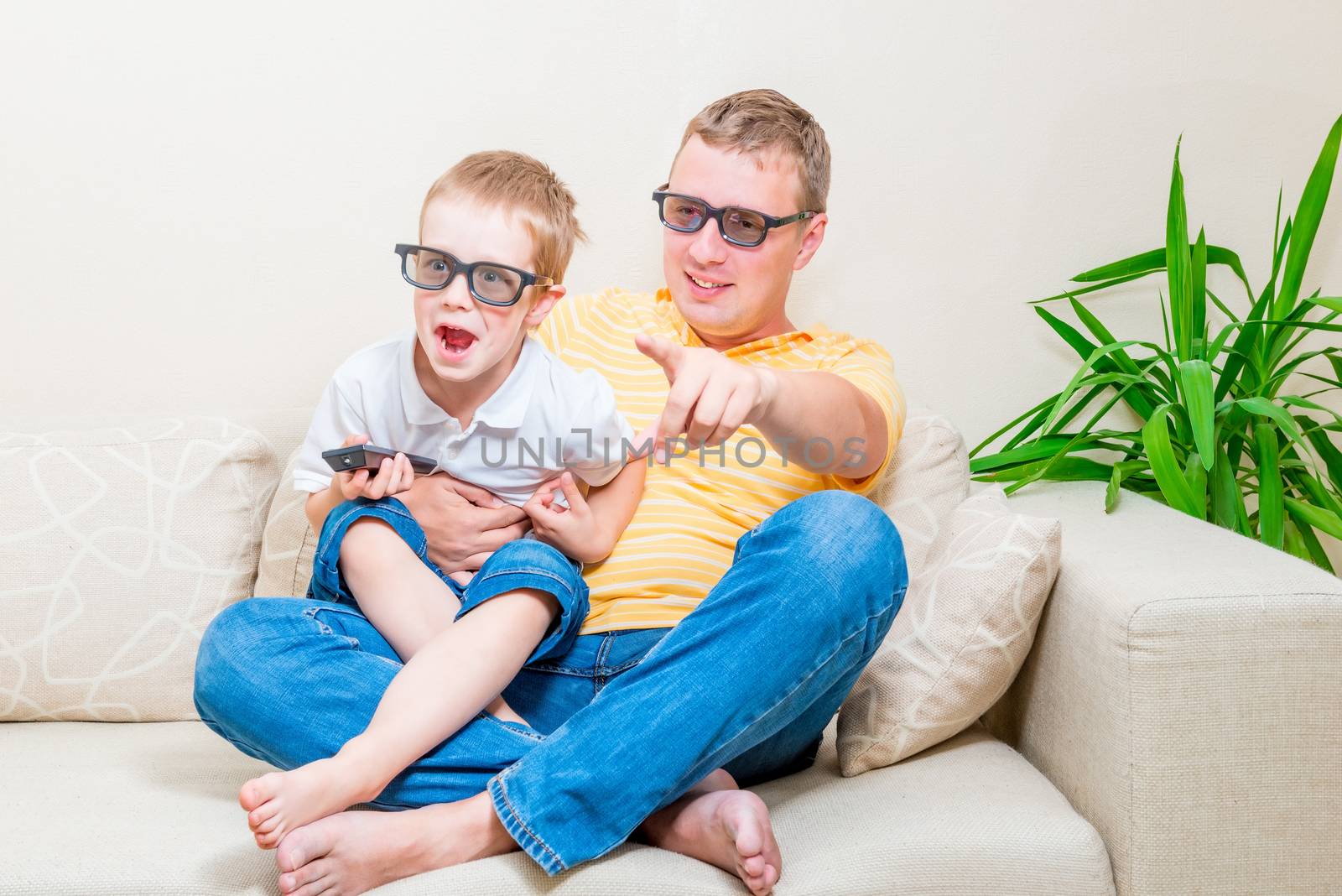 father and son in 3D glasses watching TV on the couch by kosmsos111