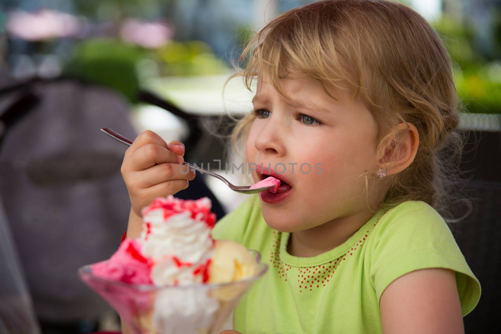 Young blond girl eating a colorful ice cream