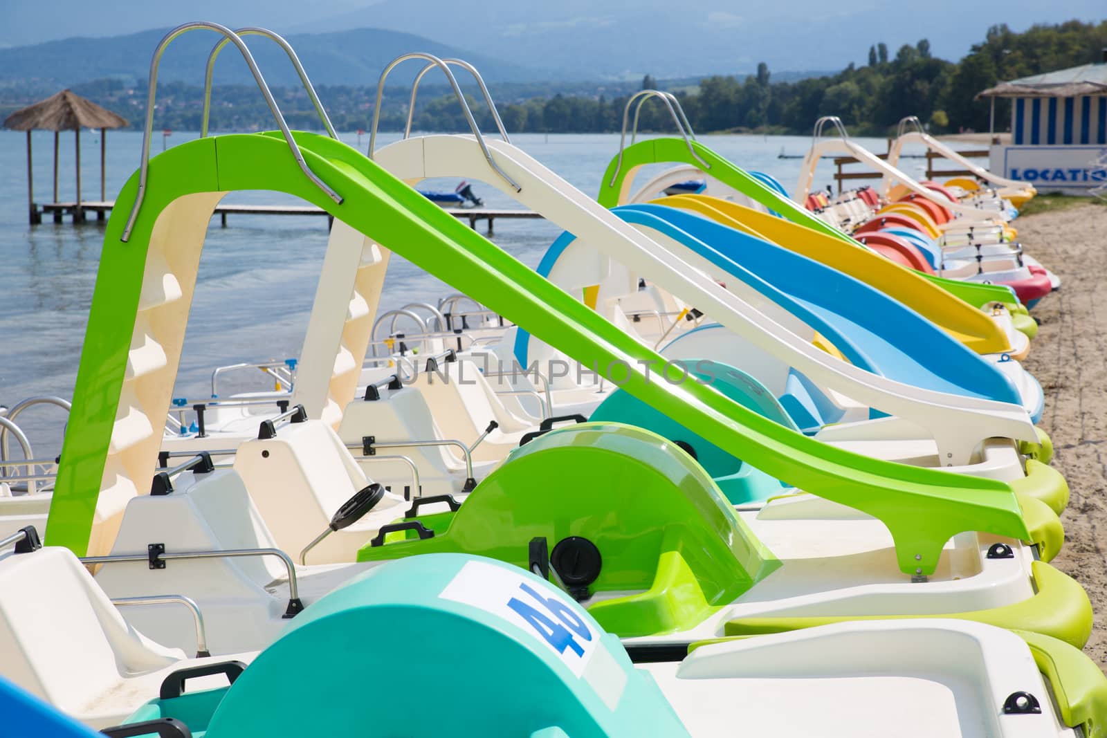 Colorful pedal boats aligned on a beach on Lake Geneva, France