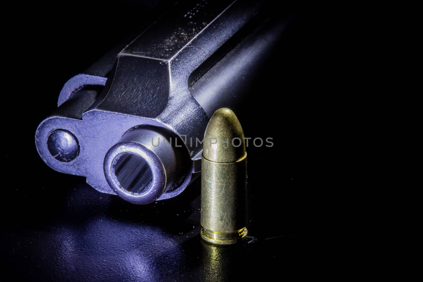 Black gun and bullets on a black background.