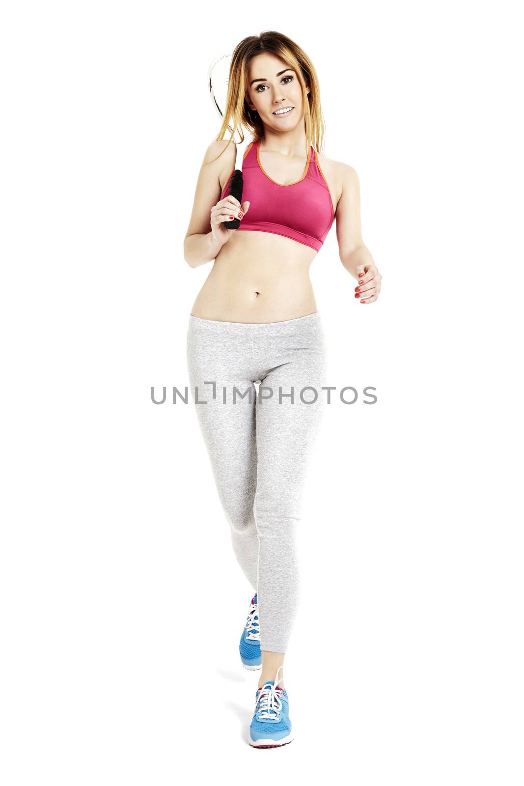 Studio shot of attractive sportswoman is walking against white background.