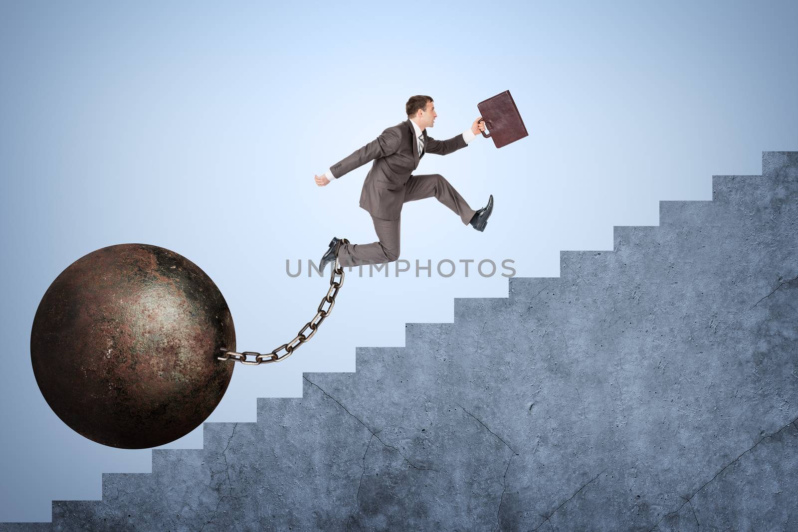 Image of confident businessman with suitcase and iron ballast running upstairs