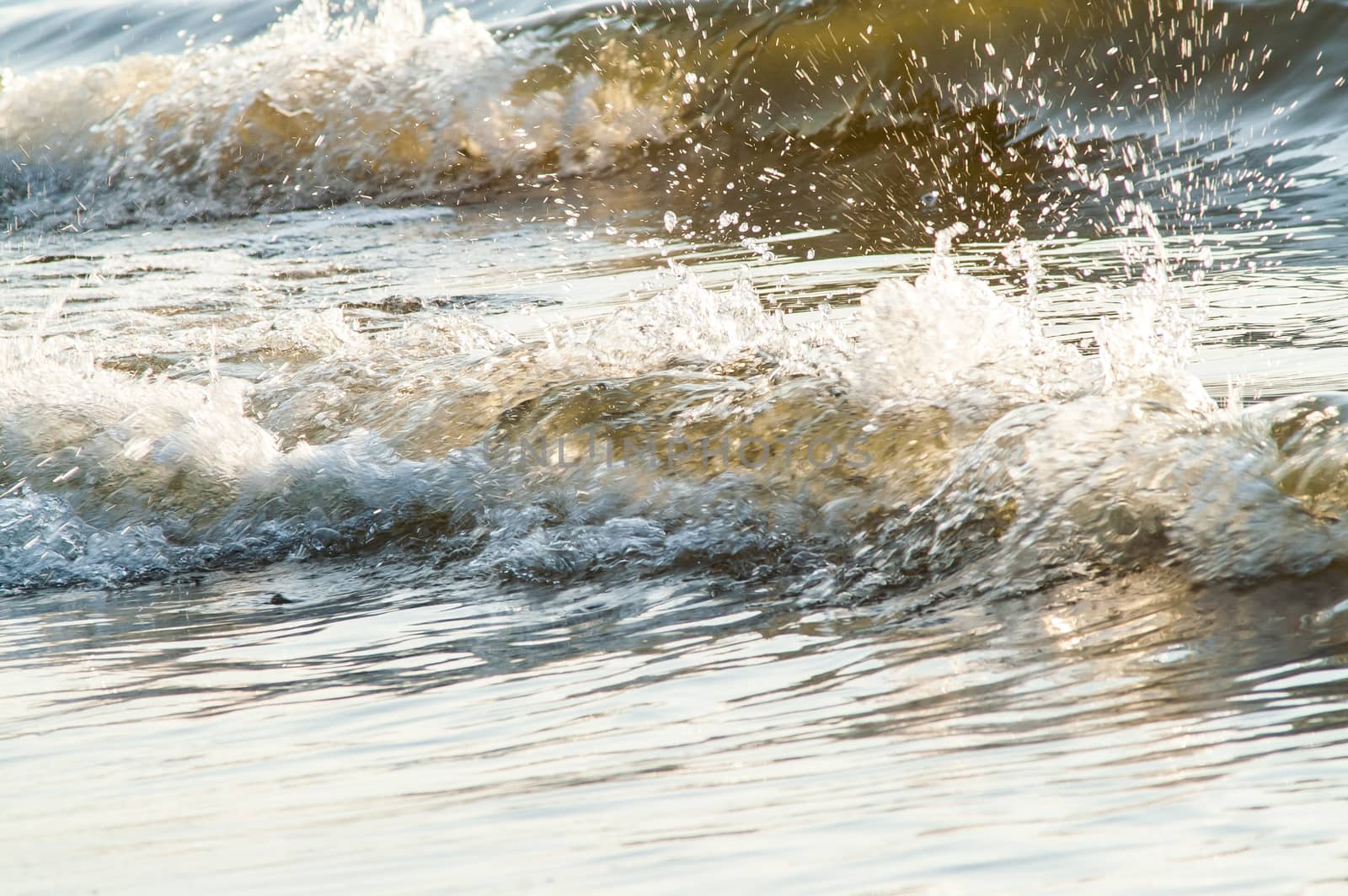 surf on a sandy beach with waves at sunset