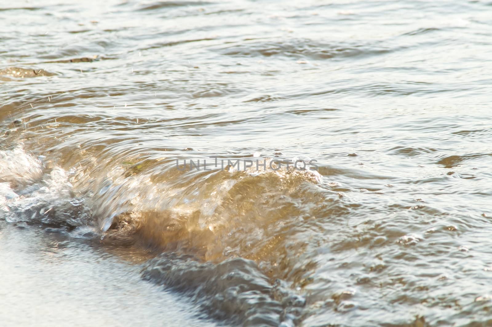 surf on a sandy beach with waves at sunset