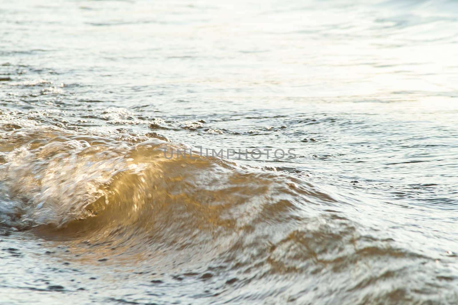 surf on a sandy beach with waves at sunset