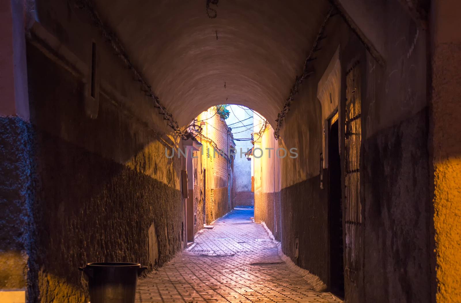 Early morning street in the downtown of Marrakesh, when the lights are still on, but its almost daylight. Dark underpass and view on enlightened street.