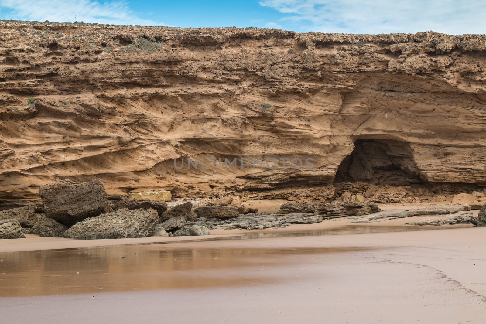 Golden sand with with water from the ocean, after a tide. Rocks on the beach. Atlantic ocean coast, Morocco.