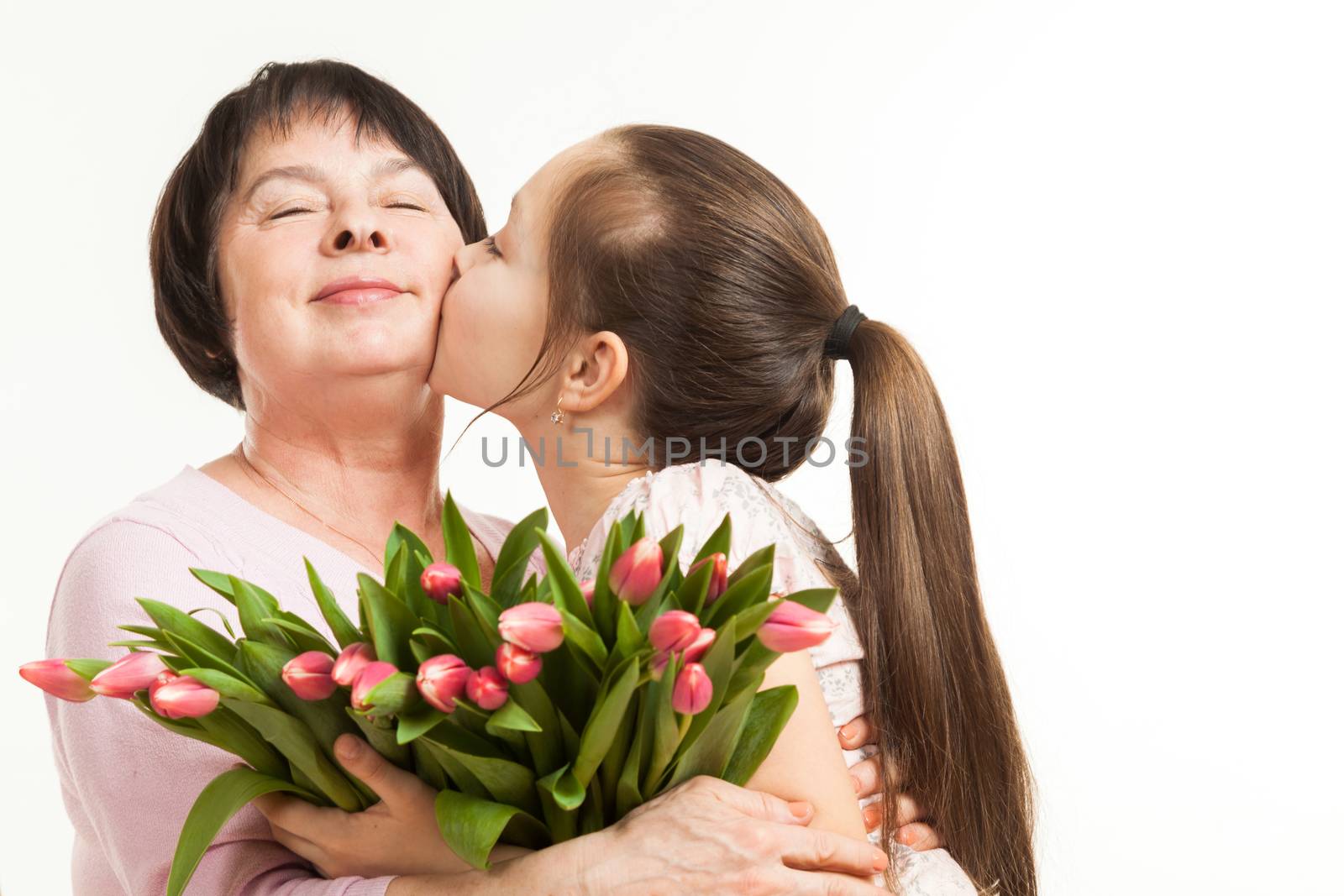 the granddaughter kisses the grandmother and gives it flowers
