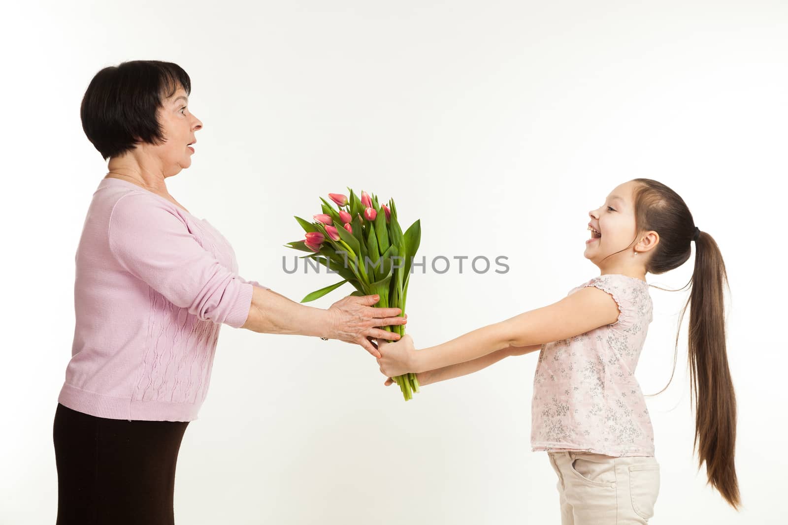 the granddaughter congratulates the grandmother and gives it flowers